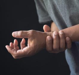 Mężczyzna kurczowo trzyma się za nadgarstek, cierpi na zespół Guillaina-Barrégo.