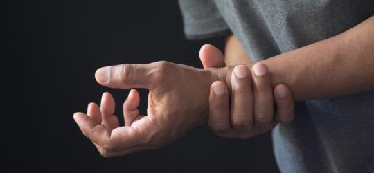 Mężczyzna kurczowo trzyma się za nadgarstek, cierpi na zespół Guillaina-Barrégo.