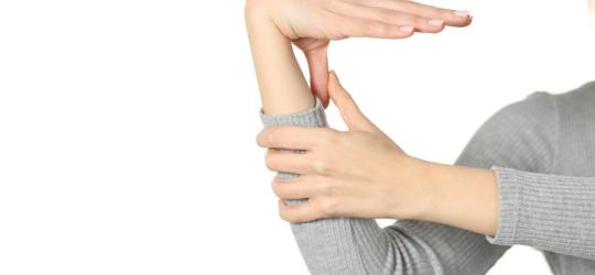 Kobieta przyciąga kciuk do przedramienia.