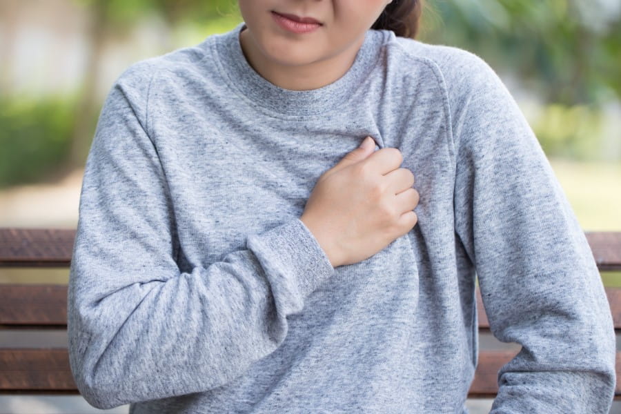 Kobieta odczuwa ból w klatce piersiowej, przyciska rękę do żeber.