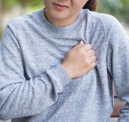 Kobieta odczuwa ból w klatce piersiowej, przyciska rękę do żeber.