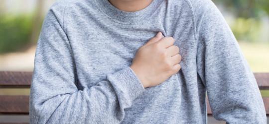 Kobieta odczuwa ból w klatce piersiowej, przyciska rękę do żeber.