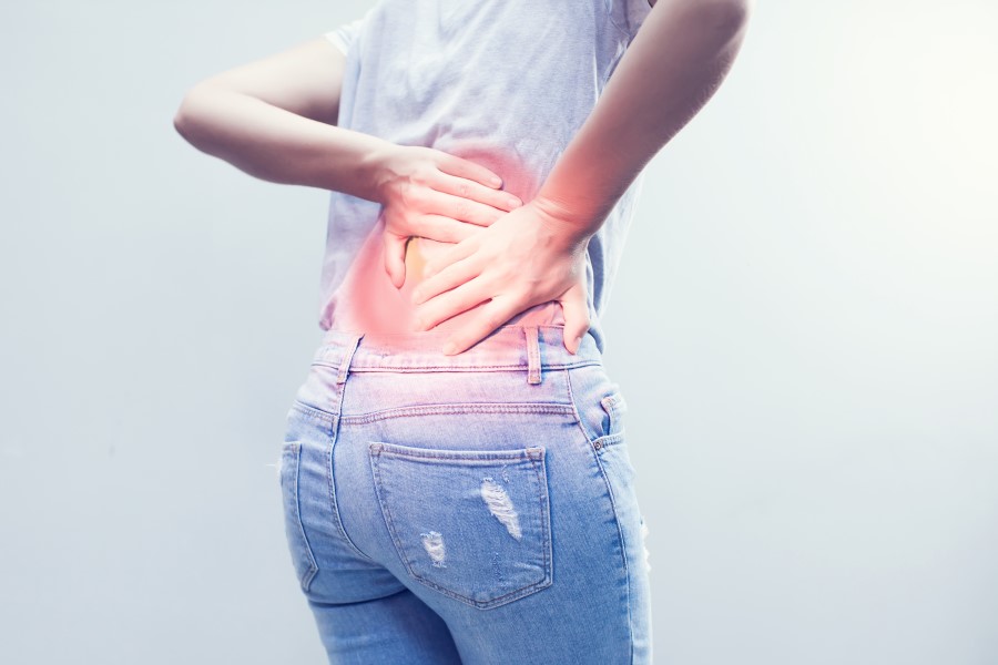 Kobietę bolą plecy, cierpi na zesztywniające zapalenie stawów kręgosłupa.