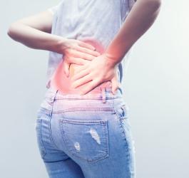 Kobietę bolą plecy, cierpi na zesztywniające zapalenie stawów kręgosłupa.