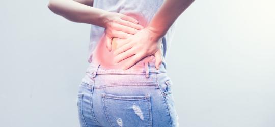 Kobietę bolą plecy, cierpi na zesztywniające zapalenie stawów kręgosłupa.