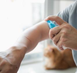 Mężczyzna dezynfekuje ranę na przedramieniu.