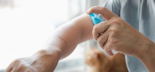 Mężczyzna dezynfekuje ranę na przedramieniu.