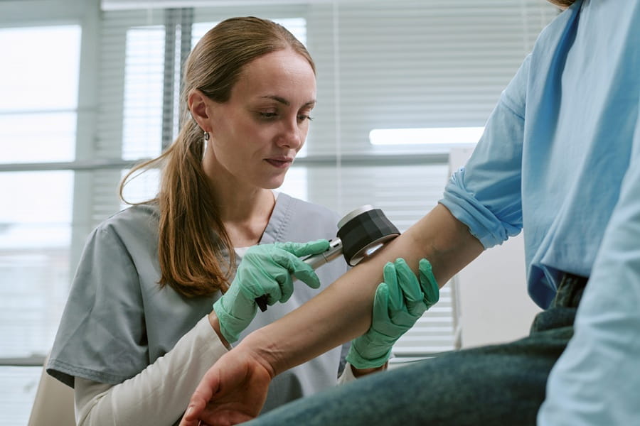 Dermatolożka przeprowadza u pacjenta dermatoskopię zmian barwnikowych.
