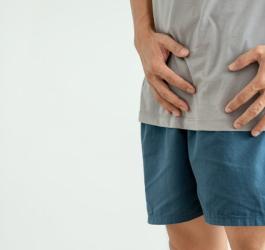 Mężczyzna trzyma się za podbrzusze, odczuwa dolegliwości spowodowane żylakami powrózka nasiennego.